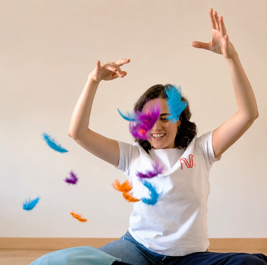 Lorena, sentada en el suelo, lanza al aire plumas de colores en una sesión de Música en familia