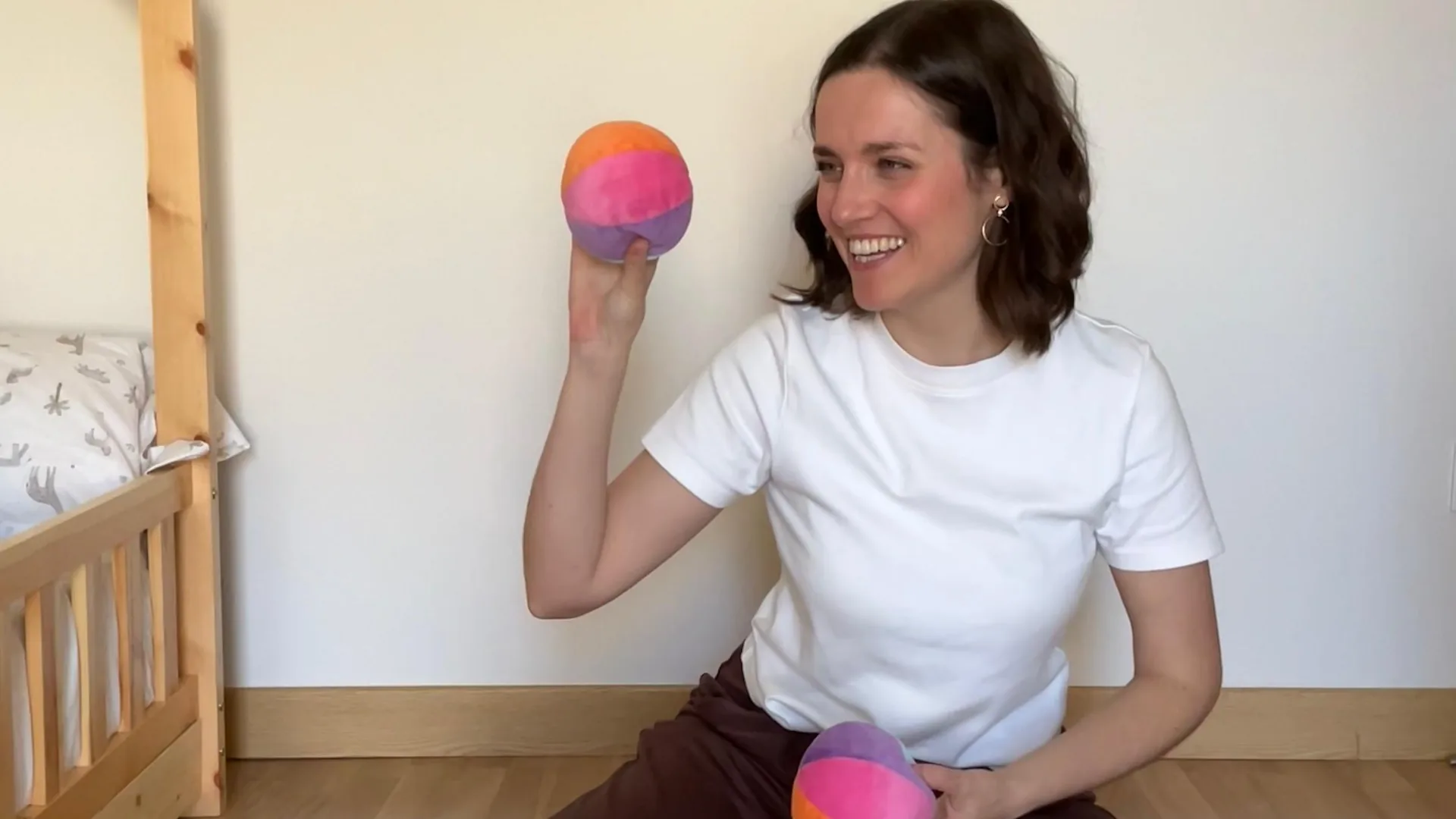 Lorena sentada en el suelo lanzando una pelota de tela de colores