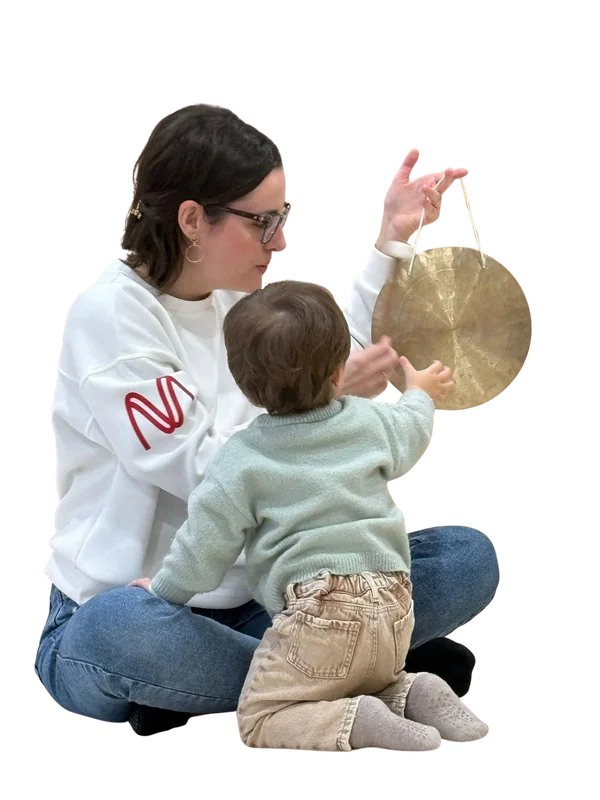 Lorena Royo haciendo sonar un gong junto a un bebé en una sesión de música en familia